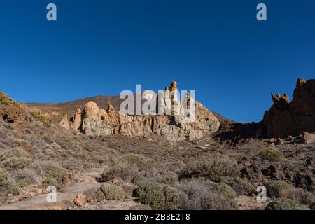 Blick auf die einzigartige Felsformation Roques de García mit dem berühmten Gipfel des Bergvulkans Pico del Teide im Hintergrund bei Sonnenaufgang, Teide National Park, Stockfoto