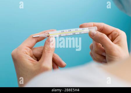 Frau hält ein Thermometer, das die Temperatur misst. Das Konzept der Viruserkrankungen. Stockfoto