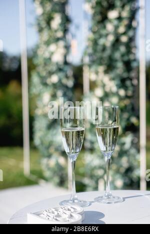 Nahaufnahme von zwei Gläsern frischen Champagner auf Holztisch auf grünem Hintergrund. Party- und Feiertagskonzept Stockfoto