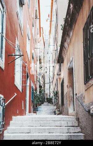 Vertikale Weitwinkelansicht einer typischen schmalen portugiesischen Straße in einem Wohnviertel von Lissabon mit Wohnhäusern auf beiden Seiten und Treppen str Stockfoto