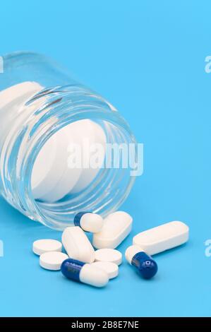 Nahaufnahme der Pillen, die aus der Pillenflasche auf blauem Hintergrund verschüttet wurden. Mit Kopierraum. Medizinkonzept . Stockfoto