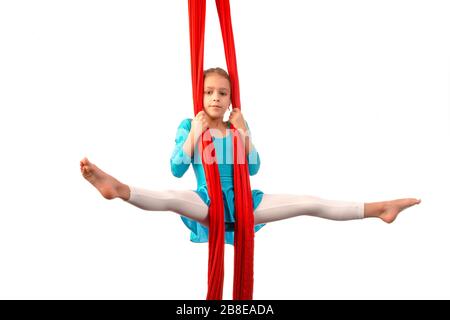 Kleines acrobat Mädchen, das sich in der Luft spaltet und an einem roten Luftband auf weißem Hintergrund hält. Akrobatikkonzept. Werbefläche Stockfoto