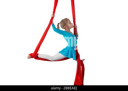 Kleines acrobat Mädchen, das sich in der Luft spaltet und an einem roten Luftband auf weißem Hintergrund hält. Akrobatikkonzept. Werbefläche Stockfoto