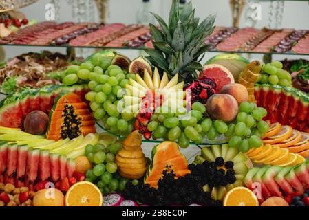 Horizontale Bilder verschiedener Früchte auf festlichen Tischen mit Trauben, Beeren, Mango, Wassermelone, Granatapfel. Feier oder andere Veranstaltung. Hochzeitstabl Stockfoto