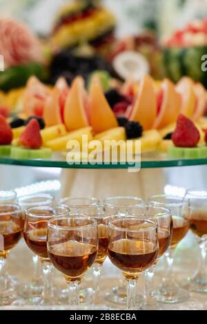 Alkoholischer Cocktail auf festlichem Tisch mit Wassermelone, Trauben, Bananen und verschiedenen frischen Früchten. Feier oder andere Veranstaltung Stockfoto