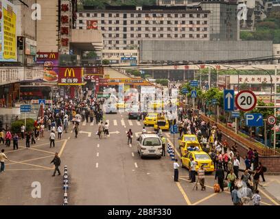 Chongqing, China - 9. Mai 2010: Stadtzentrum. Gelbe Taxis fallen und bringen Passagiere in belebter Straße mit einer Masse von Fußgängern und Geschäfts- und Wohnplätzen B. Stockfoto