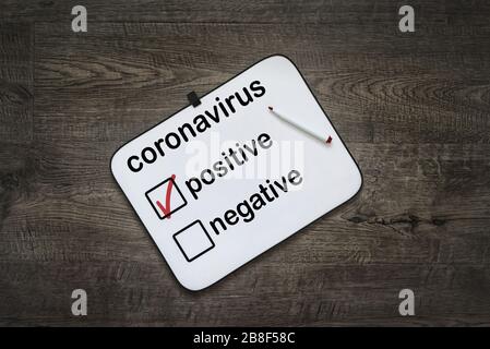 Weißes Brett mit positiven Testergebnissen für Coronavirus auf dunklem Holzhintergrund .Coronavirus COVID-19-Konzept. Gefährliches chinesisches nCoV-Coronavirus Stockfoto