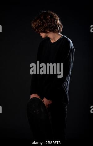 Körperaufnahme eines attraktiven männlichen Modells, das sein elegantes Skateboard hält Stockfoto