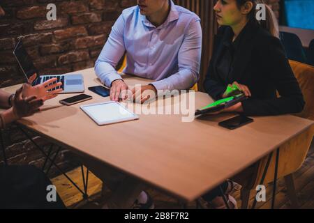 Bild mit Fokus auf einen Tisch in einer Cafeteria mit Geschäftsleuten, Tablets, Laptops und Smartphones Stockfoto
