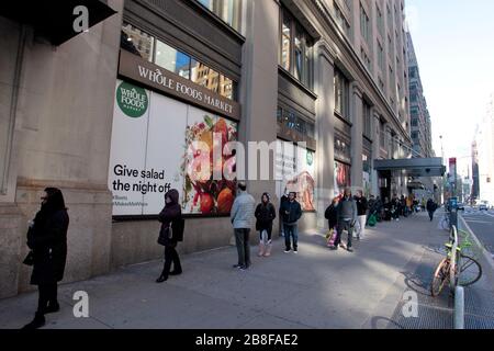 New York City, New York, Vereinigte Staaten. März 2020. Linien bildeten sich, um in den Whole Foods Supermarkt in der Chelsea Nachbarschaft von Manhattan in New York City zu gelangen, da New Yorker neue Realitäten im Zusammenhang mit der Coronavirus Pandemie konfrontierte. Der Store führte eine Richtlinie ein, die Kunden in akzeptablen Abständen online warten ließ, um große Menschenmengen im Laden und die Nähe zwischen den Käufern beim Auschecken zu vermeiden. Credit: Adam Stoltman/Alamy Live News Stockfoto