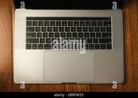 Eine Tastatur eines dunkelgrauen, silbernen Laptops, die isoliert ist Ein Holzhintergrund Stockfoto