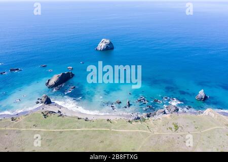 Der scheinbar friedliche Pazifische Ozean weht gegen die felsige Nordkalifornische Küste. Dieses wilde Gebiet hat eine inspirierend zerklüftete Landschaft. Stockfoto