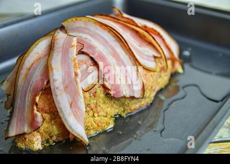 Fleischbrot mit Speckscheiben. Hausgemachte Fleischbraten auf Bratpfanne. Nahaufnahme. Stockfoto