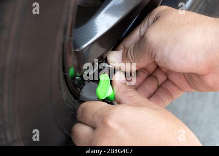 Aufblasen von Autoreifen, Nahansicht der Hände. Ein Autoservice. Stockfoto