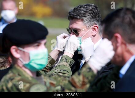 (200322) -- ZAGREB, 22. März 2020 (Xinhua) -- Der kroatische Präsident Zoran Milanovic (2. R) trägt mit Hilfe eines Soldaten eine Maske, während er ein von Soldaten errichtetes Sanitätslager inspiziert, um COVID-19-Patienten auf dem Parkplatz des Clinical Hospital Dubrava in Zagreb, Kroatien, am 21. März 2020 unterzubringen. Kroatien bestätigte 78 neue Fälle von COVID-19-Infektionen in den letzten 24 Stunden am Samstagnachmittag, die Gesamtzahl liegt jetzt bei 206. Seit Beginn des Ausbruchs am 25. Februar ist es der größte tägliche Anstieg der bestätigten Fälle. (Sanjin Strukic/Pixsell über Xinhua) Stockfoto