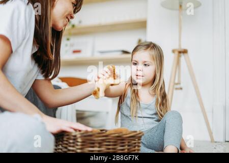 Niedliches kleines Mädchen langes faires Haar große graue Augen tragen Pyjamas spielen Löwenspielzeug mit Mutter im Zimmer bleiben Sie zu Hause Stockfoto