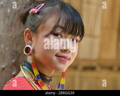 Hübsches Mädchen im Teenager-Alter von Karen Kayaw (Kayor) mit traditionellen Thanaka Gesicht auf ihren Wangen und markanten Tribal Ohrenstöpseln lächelt für die Kamera. Stockfoto