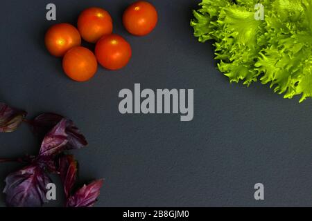 Frische Kirschtomaten und Basilikumblatt auf schwarzem Schiefersteinchalkboard mit Copyspace. Gesunde italienische Zutaten für traditionellen Caprese Salat. Organisch Ich Stockfoto