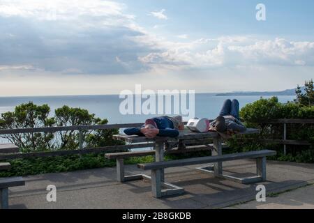 Ein Paar nimmt ein Nickerchen auf einem Picknicktisch am Muir Beach Overlook in Marin County, CA. Stockfoto