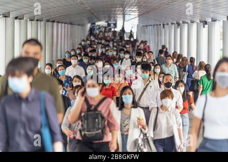 BANGKOK, THAILAND - MAR 2020: Menschenmenge von nicht erkennbaren Geschäftsleuten, die eine chirurgische Maske tragen, um einen Ausbruch von Coronavirus in der Hauptverkehrszeit zu verhindern Stockfoto