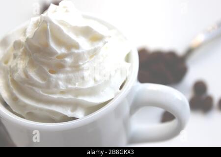 Nahaufnahme von Espresso mit Schlagsahne. Im Hintergrund Kaffeekörner Stockfoto