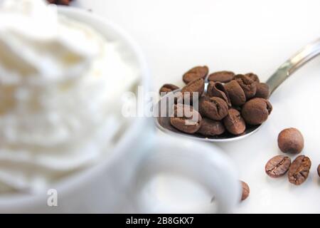 Nahaufnahme von Espresso mit Schlagsahne. Im Hintergrund Kaffeekörner Stockfoto