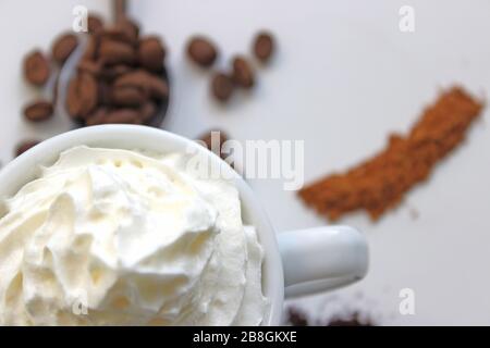 Nahaufnahme von Espresso mit Schlagsahne. Im Hintergrund Kaffeekörner Stockfoto