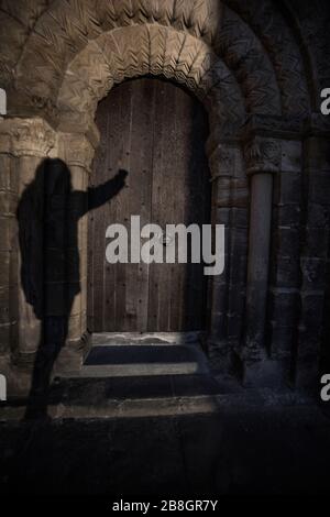 Schatten einer Person, die auf die gewölbte Holztür klopft, die zur mittelalterlichen Abtei führt, in der historischen Hauptstadt Dunfermline; Königreich Fife; Fife; SC Stockfoto