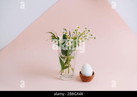 Langer Schuss eines weißen Eies in einem Holzeierstand über rosafarbener Oberfläche Stockfoto