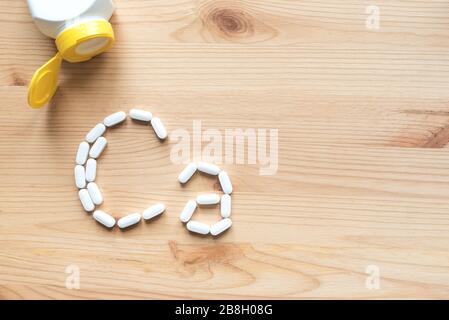 Kalziumtabletten. Weiße Pillen, die sich in Form eines Ca-Alphabets auf Holzhintergrund bilden, Kopierraum, Draufsicht. Stockfoto
