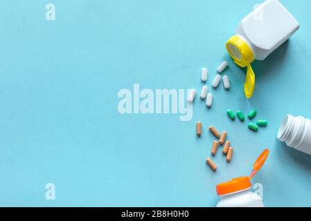 Pillenflaschen und verschiedene Pillen auf blauem Hintergrund, Draufsicht, Kopierraum. Medizin- und Apothekenkonzept. Vitamine oder generische Tabletten. Stockfoto