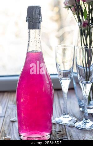 Strahlend brillantes Himbeer-Getränk. Sekt in zwei Gläsern steht auf einem Holztisch mit Eis. Für Blumen und eine Girlande. Kopierbereich Stockfoto
