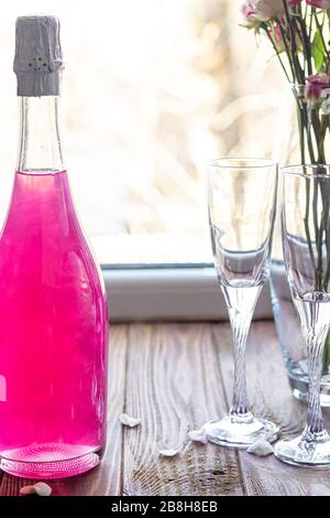 Strahlend brillantes Himbeer-Getränk. Sekt in zwei Gläsern steht auf einem Holztisch mit Eis. Für Blumen und eine Girlande. Kopierbereich Stockfoto