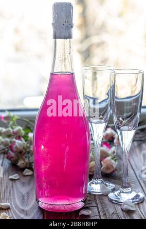 Strahlend brillantes Himbeer-Getränk. Sekt in zwei Gläsern steht auf einem Holztisch mit Eis. Für Blumen und eine Girlande. Kopierbereich Stockfoto
