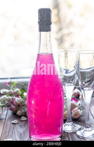 Strahlend brillantes Himbeer-Getränk. Sekt in zwei Gläsern steht auf einem Holztisch mit Eis. Für Blumen und eine Girlande. Kopierbereich Stockfoto