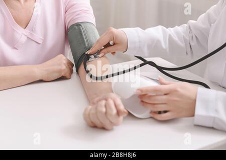 Arzt zur Messung des arteriellen Blutdrucks bei einem leitenden Patienten Stockfoto