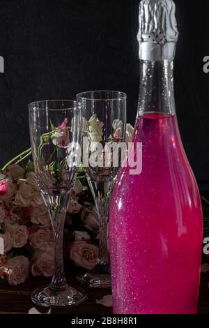 Strahlend brillantes Himbeer-Getränk. Sekt in zwei Gläsern steht auf einem Holztisch mit Eis. Für Blumen und eine Girlande. Kopierbereich Stockfoto