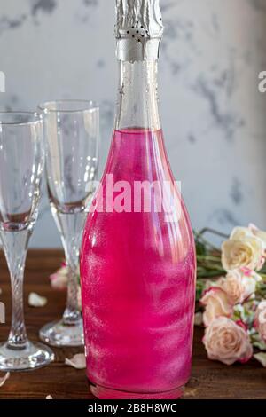 Strahlend brillantes Himbeer-Getränk. Sekt in zwei Gläsern steht auf einem Holztisch mit Eis. Für Blumen und eine Girlande. Kopierbereich Stockfoto