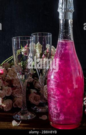 Strahlend brillantes Himbeer-Getränk. Sekt in zwei Gläsern steht auf einem Holztisch mit Eis. Für Blumen und eine Girlande. Kopierbereich Stockfoto
