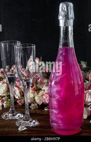 Strahlend brillantes Himbeer-Getränk. Sekt in zwei Gläsern steht auf einem Holztisch mit Eis. Für Blumen und eine Girlande. Kopierbereich Stockfoto