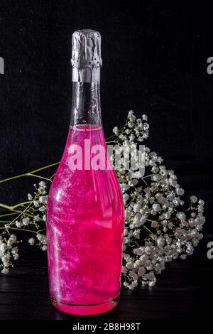 Strahlend brillantes Himbeer-Getränk. Sekt in zwei Gläsern steht auf einem Holztisch mit Eis. Für Blumen und eine Girlande. Kopierbereich Stockfoto