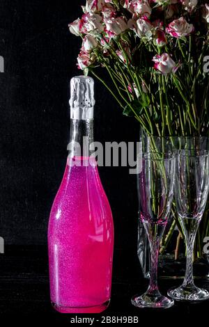 Strahlend brillantes Himbeer-Getränk. Sekt in zwei Gläsern steht auf einem Holztisch mit Eis. Für Blumen und eine Girlande. Kopierbereich Stockfoto