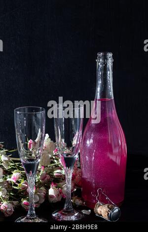 Strahlend brillantes Himbeer-Getränk. Sekt in zwei Gläsern steht auf einem Holztisch mit Eis. Für Blumen und eine Girlande. Kopierbereich Stockfoto