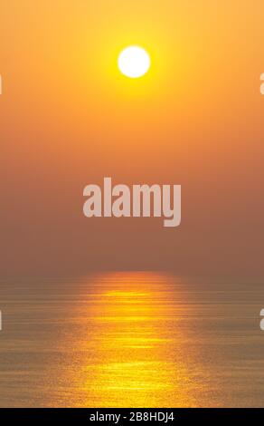 Der Sonnenuntergang, die Meeresoberfläche reflektiert das Sonnenlicht in Gold. Klarer Himmel, Orange ohne Wolken Stockfoto