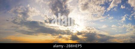 Sonne, die durch Wolken in einem blauen Himmel platzt. Stockfoto