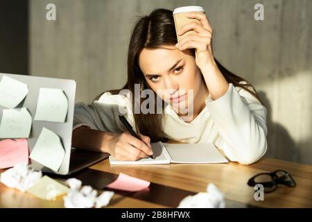 Müde Mädchen hat keine Ideen und hält Kaffee Stockfoto