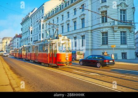 WIEN, ÖSTERREICH - 19. FEBRUAR 2019: Die retro-rote Straßenbahn fährt am 19. Februar auf der Rennwegstraße, gesäumt von prächtigen Wiener Bauen und Herrenhäusern Stockfoto