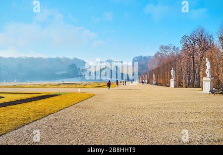 WIEN, ÖSTERREICH - 19. FEBRUAR 2019: Gasse des Ziergartens Schönbrunn (große Parterre) mit antiken Statuen, Blumenbeeten und Gloriette auf Stockfoto