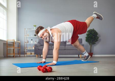 Lustiger fetter Mann, der Yoga-Übungen im Raum macht. Stockfoto