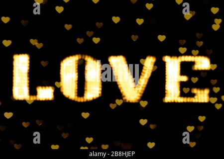 Verschwommener Text Gelb Gold LOVE Sign LED Bokeh Neon hell gelb Gold auf Hintergrund Bokeh leuchtet Herz weich bunt Stockfoto